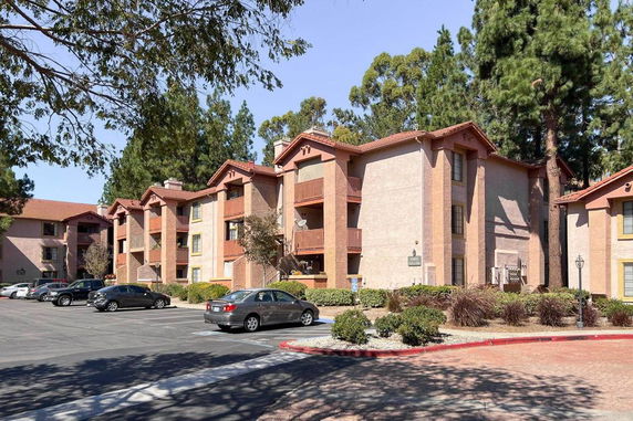 Front view of a multi-story apartment building with a parking area in front.