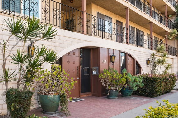Front view of a multi-story building with balconies and decorative plants.