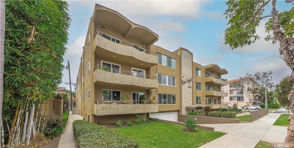 Front view of a multi-story apartment building with balconies and a garage entrance.
