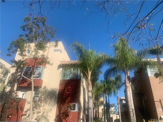 Front view of a multi-story apartment building with palm trees.