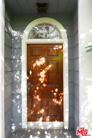 Front view of a house entrance with a wooden door and arched transom window.