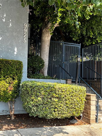 Front view of a building with a gated entrance and surrounding greenery.