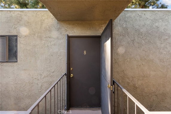Front view of a building entry door with a small window nearby.