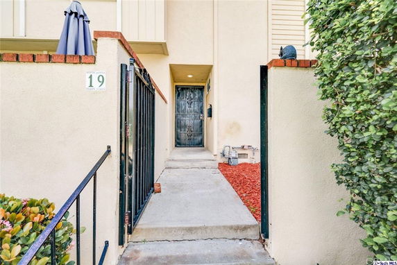 Front view of a house entrance with a metal gate and a pathway leading to the door.