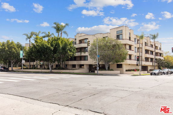 Front view of a multi-story residential building with balconies and trees.
