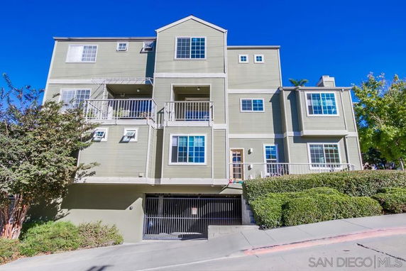 Front view of a multi-story residential building with balconies and a garage entrance.