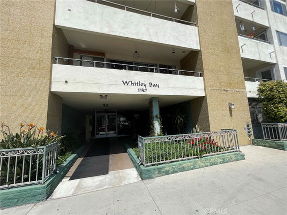 Front view of a multi-story building entrance with balconies and a sign that reads 'Whitley Bay'.