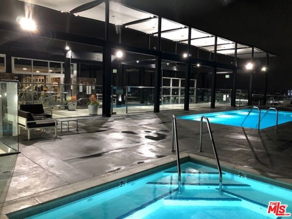 Rooftop area with illuminated swimming pools and seating.