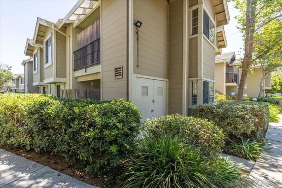 Front view of a multi-story residential building with beige siding and multiple windows.