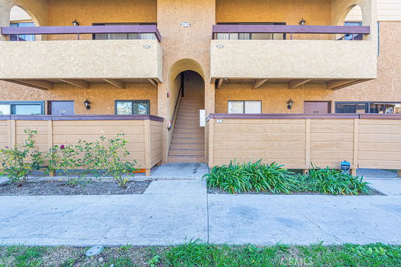 Front view of a two-story building with balconies and a staircase entrance.