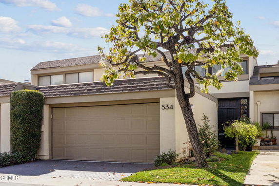 Front view of a house with a double garage and a small tree in front.