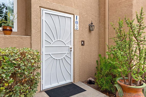 Front entrance of a house with a decorative white security door marked with the number 103.