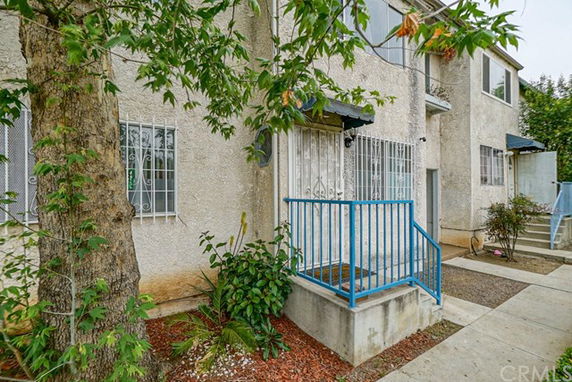 Front view of a two-story building with a small entry porch and blue railing.
