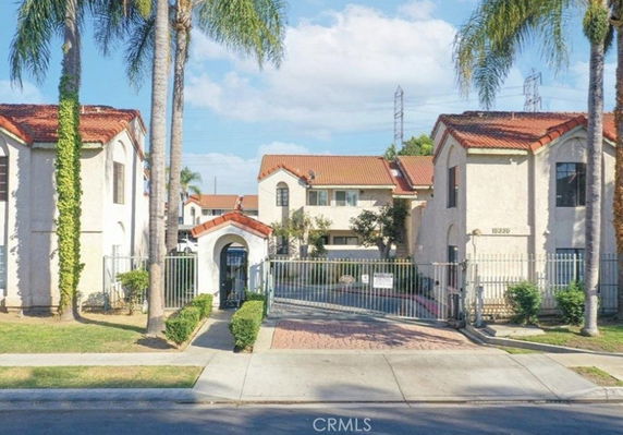 Front view of a gated multi-family housing complex with red-tiled roofs.