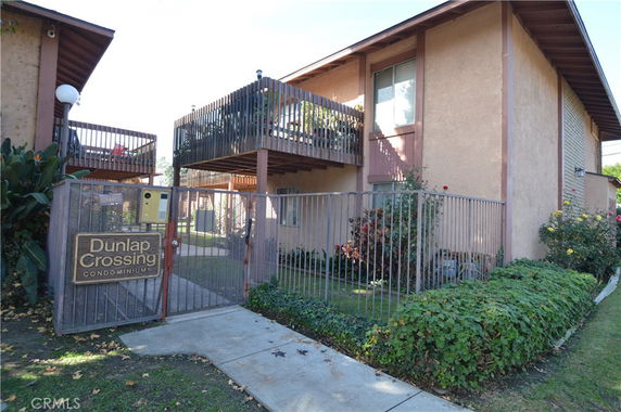 Front view of a two-story condominium building with a gated entrance.
