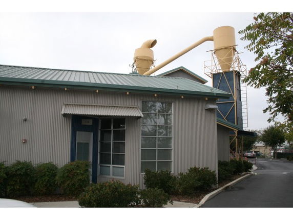 Front view of a corrugated metal building with industrial structures on the roof.