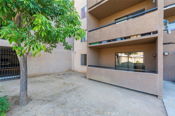 View of the exterior with covered balconies and nearby tree.