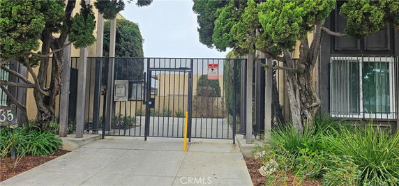 Front view of a building entrance with a gated fence and surrounding trees.