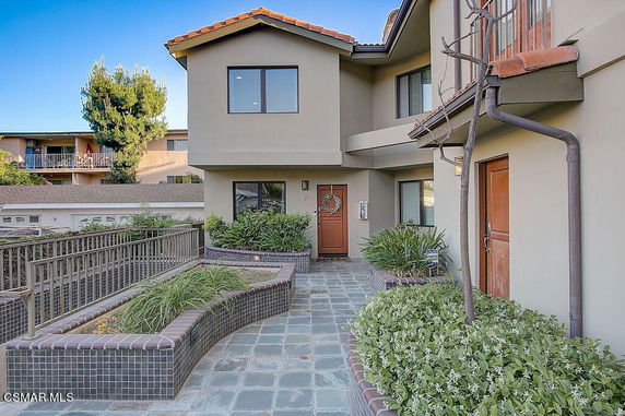 Front view of a two-story house with a tiled pathway and landscaped entrance.