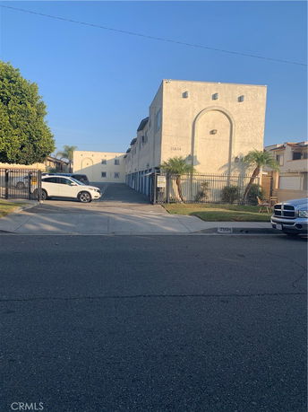 Front view of a multi-story building with a gated entrance and parked cars.