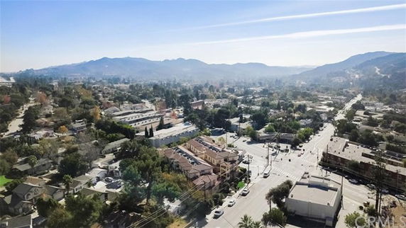 Wide-angle view of a city landscape with buildings, streets, and mountains in the background.