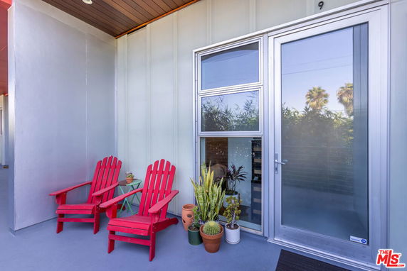 Front view of a house entrance with a glass door and a small seating area.