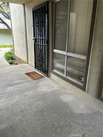 Exterior view of a building entrance with a metal security door and window with blinds.