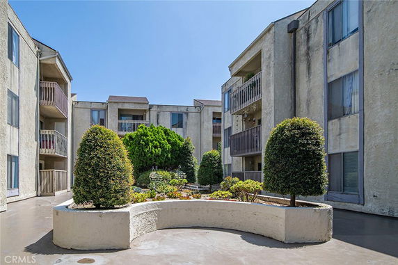 Front view of a multi-story apartment building with balconies and landscaped area.