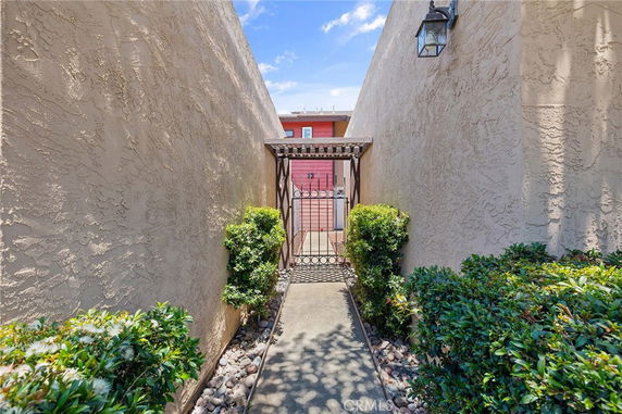 Entrance pathway with tall stucco walls leading to a gated entrance.