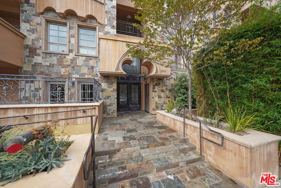 Front view of a multi-story building with stone facade and decorative metal railings.