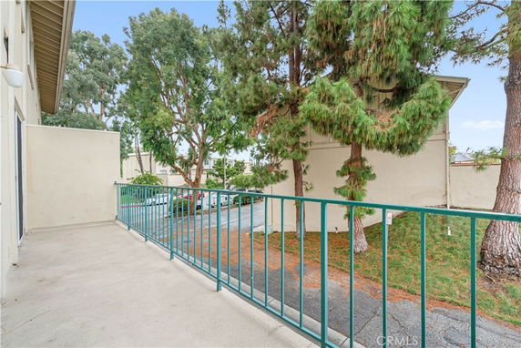 Outdoor view from a building with a balcony railing overlooking trees and adjacent structures.