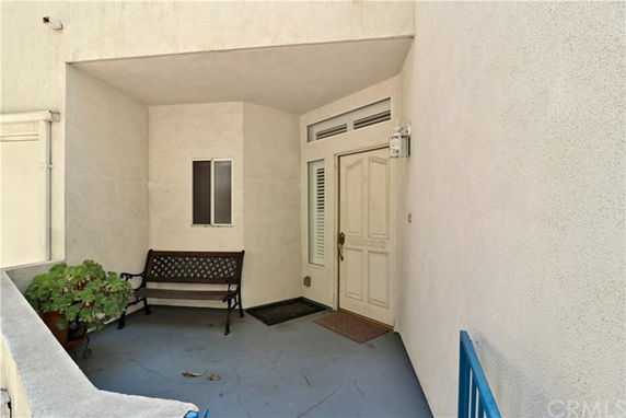 Front view of a house entrance with a bench and potted plant.