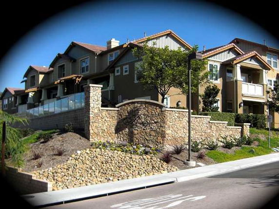 Front view of multi-story houses with stone walls and balconies.