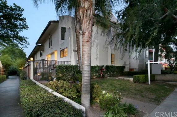 Front view of a multi-story building with a fence and surrounding greenery.