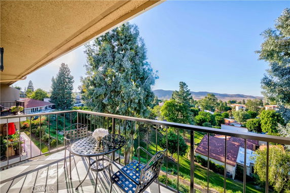 Balcony view showing surrounding landscape with trees and distant hills.