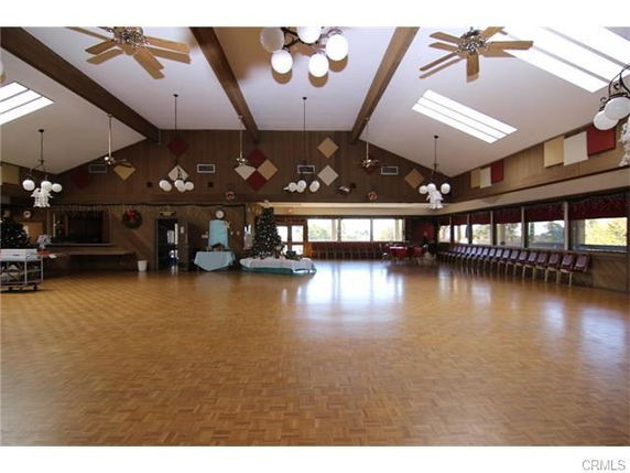 Large indoor recreation hall with wooden flooring and decorative ceiling lights.