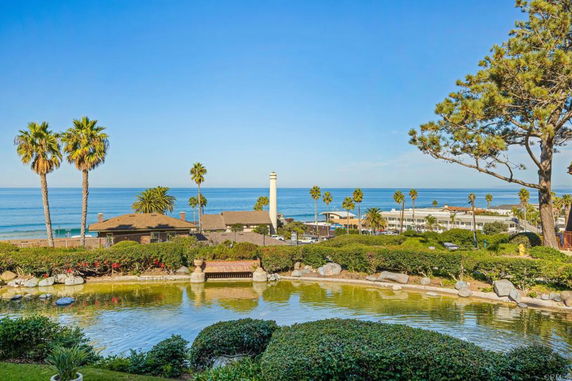 Panoramic view of a coastal area with ocean, palm trees, and buildings.