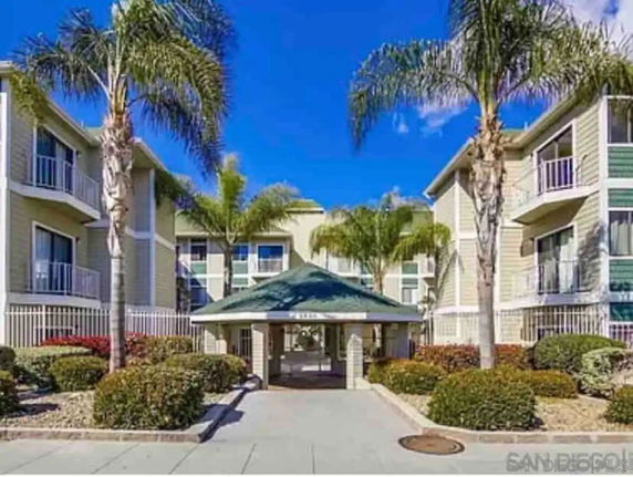 Front view of a multi-story apartment building with balconies and palm trees.