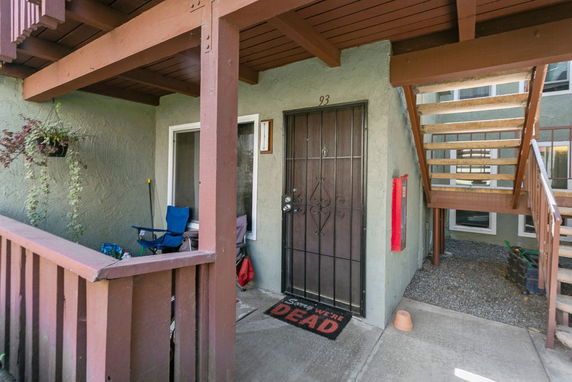 Entrance of a residential building unit with a metal door and stairs leading to an upper level.