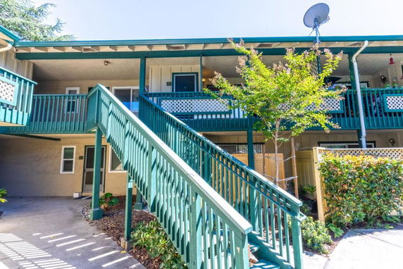 Front view of a two-story building with green railings and a staircase.