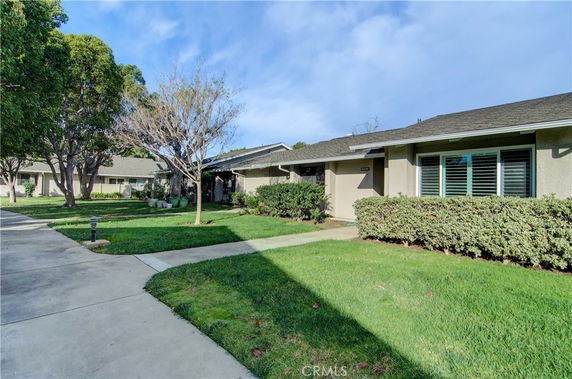 Front view of a single-story house with manicured shrubs and a walkway.