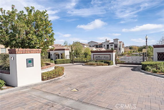 Front view of a gated residential complex with a paved entrance and landscaped surroundings.