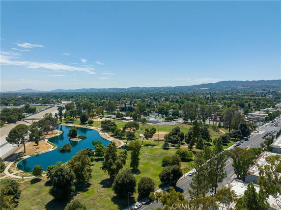 Panoramic view of a park with a pond and surrounding greenery.