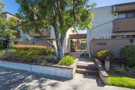 Front view of a multi-story building with wood paneling and gated entrance.