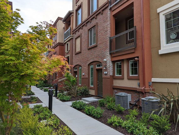 Front view of a multi-story townhouse with balconies and brick facade.