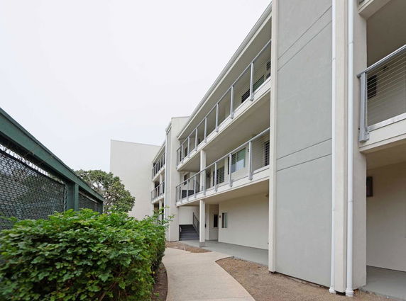 Side view of a multi-story residential building with balconies.