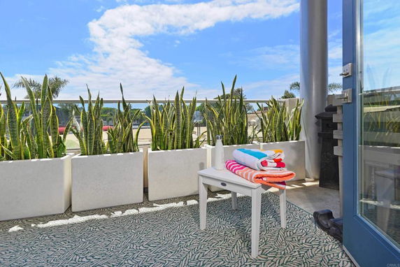 Outdoor patio area with potted plants and a small table with towels.