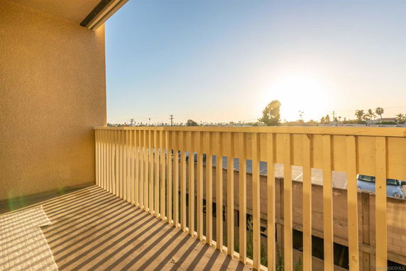 View from a balcony overlooking a parking area and distant landscape during sunset.