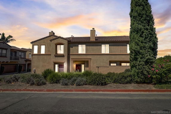 Front view of a two-story house with a brown exterior and chimney.