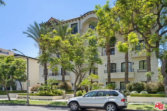 Front view of a multi-story residential building with balconies and arched windows.